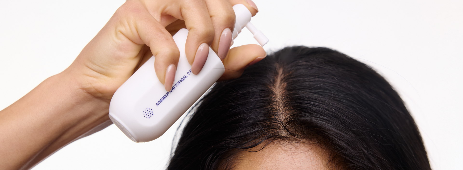 Person using a hair care product on their head with a white background