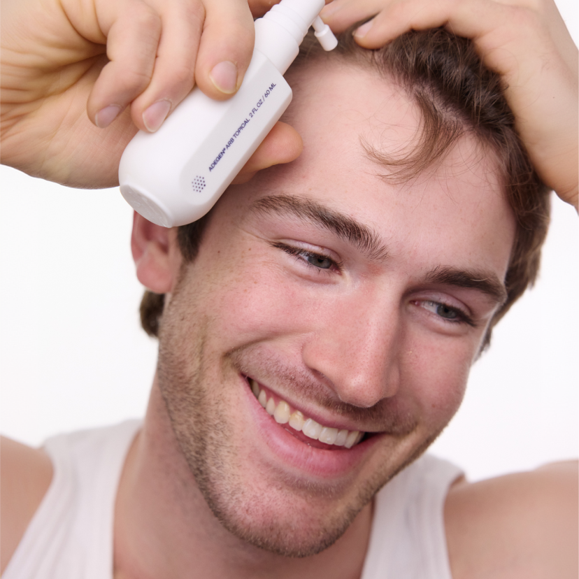 man using adegen topical formula on scalp and smiling